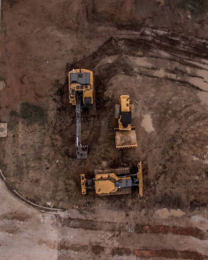 services-03 An aerial shot of heavy machinery at a construction site, including excavators and road rollers.