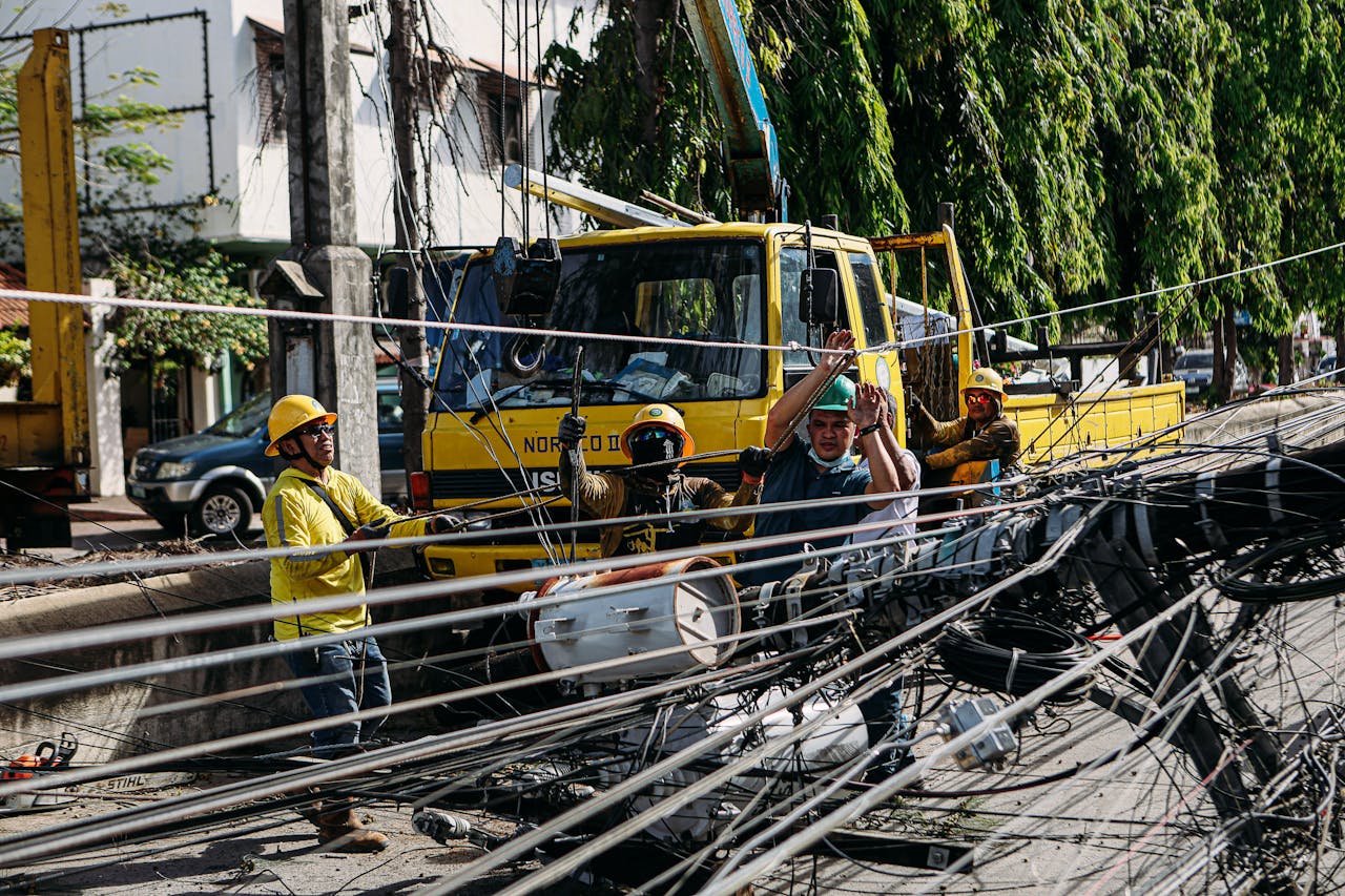 why-choose-us-02 Utility workers conduct repairs on fallen power lines with heavy machinery on a sunny day.